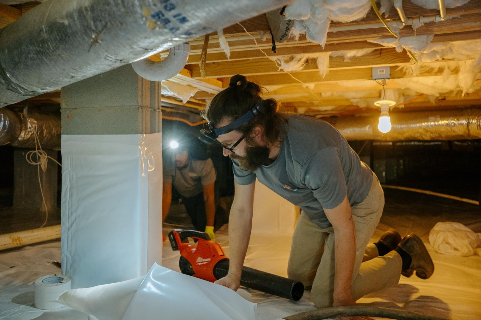 Crawlspace Medic technicians mid-installation under a home