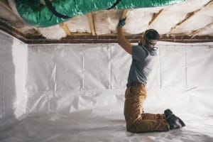 man installing insulation under home