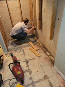 worker fixing studs in a basement bathroom