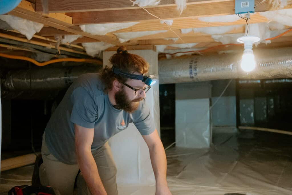 Crawlspace Medic technician sealing vapor barrier seams in Ozark Missouri crawl space